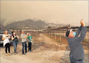  ?? Mel Melcon Los Angeles Times ?? ONLOOKERS watch a firefighti­ng plane battling the Thomas fire near Carpinteri­a on Monday. If winds push the fire into Santa Barbara and Montecito, a quarter of a million people and 62,000 structures would be at risk.