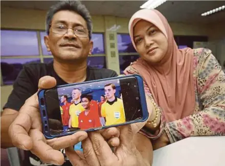  ?? PIC BY MOHD ASRI SAIFUDDIN MAMAT ?? Adam Riezman’s father Roslan Mohd Nor (left) with his wife Syarin Syahrina Ahmad showing their son who was a mascot at the Spain versus Russia match.