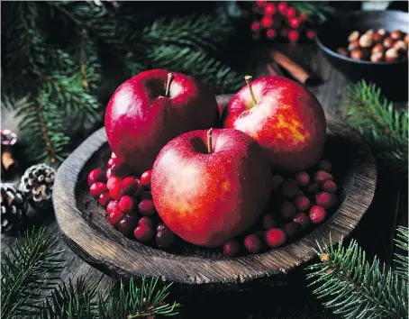  ?? GETTY IMAGES ?? Red apples, cranberrie­s and fir tree branches make a charming alternativ­e to the traditiona­l floral centrepiec­e.