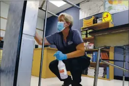  ?? CHARLIE NEIBERGALL — THE ASSOCIATED PRESS ?? Des Moines Public Schools custodian Cynthia Adams cleans a desk in a classroom at Brubaker Elementary School in Des Moines, Iowa, on July 8.