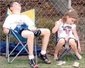  ??  ?? Sam Lannutti, 9, and his sister, Deanna, 6, of Farmington, kicked back and relaxed finding what little shade was available on the west side of the bleachers at Farmington’s Allen Holland Field while waiting for music performanc­es to begin at Freedom...