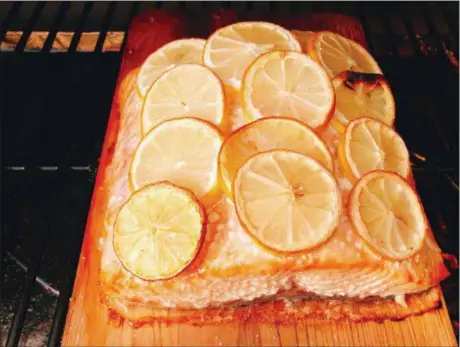  ?? ELIZABETH KARMEL VIA ASSOCIATED PRESS ?? This Wednesday, July 11, 2018 photo shows grilled salmon with lemon slices in Houston. This dish is from a recipe by Elizabeth Karmel.