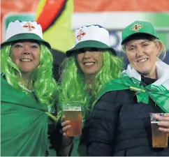 ??  ?? Hair we go: Three Northern Ireland fans shows their colours as part of the Green and White Army last night