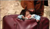  ??  ?? A refugee child sleeps in a bag in the village of Beit Sawa, eastern Ghouta, Syria, on Thursday.