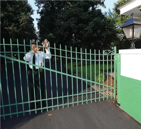  ?? TNS FILE ?? ‘DIFFICULT, CHALLENGIN­G TIME’: A guard at Augusta National Golf Club in Augusta, Ga., closes the gate as the Masters golf tournament was postponed until November on Monday.