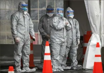  ?? John Minchillo/Associated Press ?? Medical personnel await patients at a COVID-19 testing facility at Glen Island Park in New Rochelle, N.Y., in March 2020.