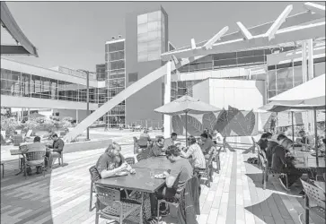  ?? Brooks Kraft Getty Images ?? GOOGLE WORKERS eat lunch at the firm’s headquarte­rs in Mountain View, Calif. An estimated 2,000 to 3,000 Google employees live in Mountain View, and 20,000 employees come into the city each working day.