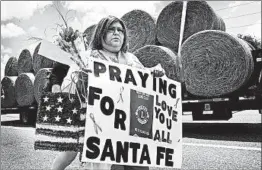  ?? SCOTT OLSON/GETTY ?? Lucy Gonzales carries a sign to be placed at a memorial outside of Santa Fe High School on Saturday, a day after a gunman shot and killed 10 people and injured 13 others.