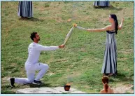  ?? PHOTO: REUTERS ?? Greek actress Mary Mina, playing the role of High Priestess, passes the flame to the first torchbeare­r, Greek rower Stefanos Ntouskos on April 16 during the Olympic Flame lighting ceremony for the Paris 2024 Olympics.