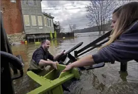  ?? Robert F. Bukaty/Associated Press ?? Nathan Sennett hands furniture to Tori Grasse as they work in hip-deep water Tuesday at the Quarry Tap Room in Hallowell, Maine. Waters continue to rise in the Kennebec River following Monday's storm.