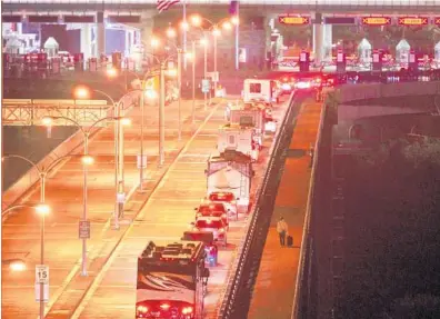  ?? GEOFF ROBINS/GETTY-AFP ?? A pedestrian walks past a line of Canadian travelers in their passenger cars or motor homes on the Rainbow Bridge between Niagara Falls, Ontario, and Niagara Falls, New York, in the early hours of Nov. 8.