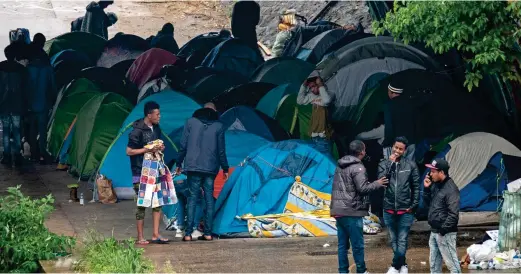  ??  ?? Makeshift camps: A group of young men congregate by their tents underneath a bridge on the banks of a Paris canal