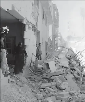  ??  ?? Syrians look at civil defence workers using a digger to look for survivors in the rubble of collapsed buildings following reported air strikes in Aleppo’s rebel-held neighbourh­ood of Tariq al-Bab (AFP Photo)