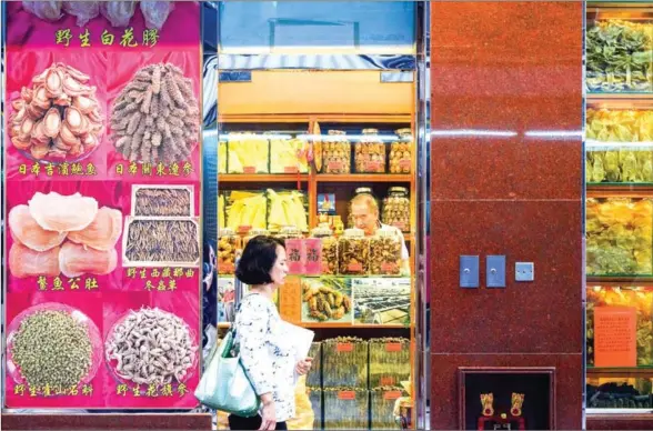  ?? ANTHONY WALLACE/AFP ?? A woman walks past a shop selling dried abalone and other dried seafood in Hong Kong on October 4.