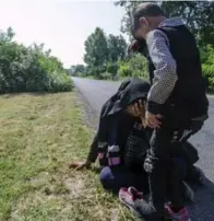  ?? CSABA SEGESVARI/AFP/GETTY IMAGES ?? A migrant family resting by the roadside in July temperatur­es of 38 Celsius in southern Hungary.