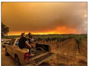  ?? (AP/Noah Berger) ?? Charles Chavira (left) and Thomas Henney watch smoke from wildfires spread over a vineyard near Healdsburg in Sonoma County, Calif., on Aug. 20.
