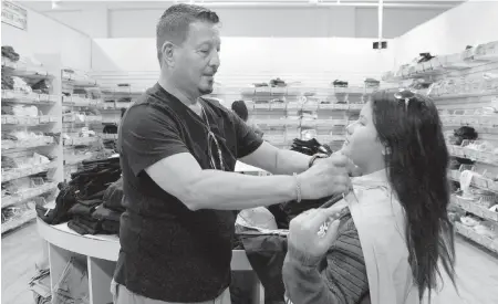  ?? CARL JUSTE / ?? Sal Salvatierr­a, left, and his daughter, Christina, 12, right, shop for school uniforms as he measures her waist by using her neck on the last day of the back-to-school tax holiday the uniform store Ibiley's inside the 163rd Street Mall in North Miami Beach on Aug. 16, 2015.