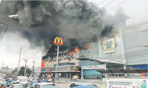  ??  ?? Smoke billows from a shopping mall on fire in Davao City, the Philippine­s. — Reuters photo
