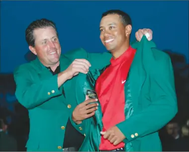  ?? The Associated Press ?? Tiger Woods, right, gets the Green Jacket from Phil Mickelson after winning the 2005 Masters at Augusta National Golf Club in Augusta, Ga. Woods is back for only the second time in the last five years, with the Masters beginning on Thursday.