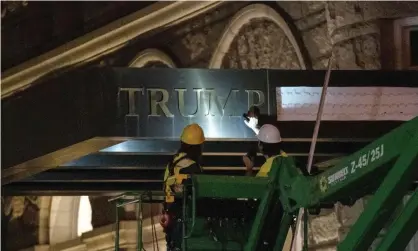  ?? ?? Workers remove signage for the Trump Internatio­nal Hotel in Washington. Photograph: Gemunu Amarasingh­e/AP