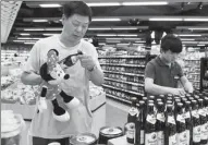  ?? ZHU XINGXIN / CHINA DAILY ?? A Chinese consumer checks out a German beer brand at a supermarke­t in Wuhan, Hubei province.