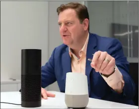  ?? Mark Lennihan/AP ?? Alexa checks balances? Gareth Gaston, Executive Vice President and Head of Omnichanne­l Banking at US Bank, discusses voice assistant banking with an Amazon Echo, left, and a Google Home, right, in New York. Big banks and financial companies have...