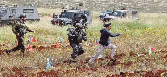  ?? [ FOTO REUTERS ] ?? Tentera sempadan Israel mengejar seorang peneroka Yahudi selepas pertempura­n dengan warga Palestin di sebuah kawasan penempatan dekat Ramallah, di Tebing barat, semalam.