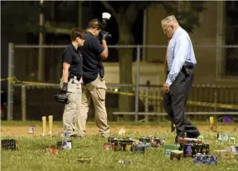  ?? JIM MICHAUD PHOTOS / BOSTON HERALD FILE ?? ‘SENSELESS’: Police work July 4 among evidence markers and fireworks debris at Mary Hannon Playground in Roxbury, where an 8-year-old girl and 35-year-old man were injured in a shooting. Left, police Commission­er William Gross speaks to a woman at the scene.