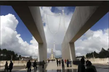  ?? PAULO DUARTE — THE ASSOCIATED PRESS ?? Pilgrims walk by a 26 metre tall giant glow-in-the-dark rosary, titled “Suspension” by the Portuguese artist Joana Vasconcelo­s, above the entrance of Basilica of the Holy Trinity, in Fatima, Portugal, Thursday. Pope Francis is visiting the Fatima...