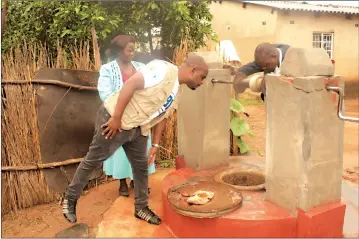  ??  ?? Mazowe district nutritioni­st Mr Shingirai Mikiri (left) assesses the water level in a protected well at Mrs Gwaze’s (in blue dress) homestead.