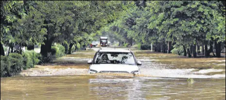  ?? VIPIN KUMAR/HT PHOTO ?? A car wades through a flooded stretch in Delhi’s Dwarka on Saturday.