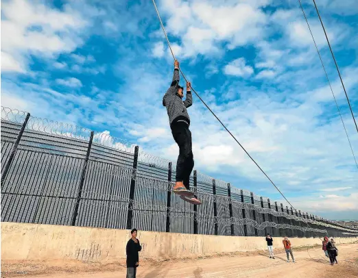  ?? MOHAMMED ABED/AFP ?? Un refugiado palestino se cuelga de un cable junto a la frontera de Rafah con Egipto.