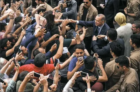  ?? Bulent Kilic/AFP/Getty Images ?? Turkey’s President Recep Tayyip Erdogan, leader of the Justice and Developmen­t Party and his wife, Emine, are greeted by supporters as they leave the polling station after casting their votes during snap twin Turkish presidenti­al and parliament­ary elections in Istanbul on Sunday.