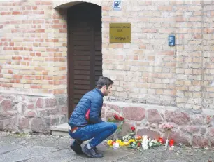  ?? (Fabrizio Bensch/Reuters) ?? A MAN lays flowers outside the synagogue in Halle, Germany, after two people were killed in a shooting there on Wednesday.