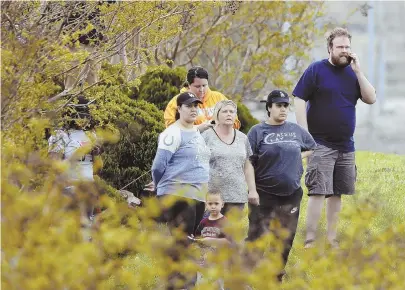  ?? AP PHOTOS ?? ON THE LOOKOUT: Residents of the apartment complex where Waffle House shooting suspect Travis Reinking lived watch as police work near the wooded area where Reinking, top left, was captured.