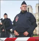  ?? AP PHOTO ?? Police officers seal off the access to Notre Dame Cathedral, seen in the background, after a man attacked officers with a hammer outside the famous landmark in Paris yesterday.