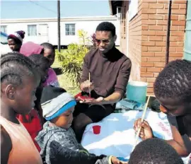  ??  ?? Bhekabasem­bo Christian Mkhize painting the South African flag with children of Ithembales­izwe Community Care Centre