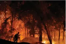  ?? Associated Press ?? ■ A firefighte­r battles the Maria Fire on Oct. 31 in Somis, Calif. Since leaders first started talking about tackling the problem of climate change, the world has spewed more heat-trapping gases, gotten hotter and suffered hundreds of extreme weather disasters. Fires have burned, ice has melted and seas have grown.