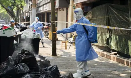  ?? ?? Workers in protective gear disinfect a pile of rubbish in Shanghai, China, as part of measures to tackle Covid-19. Photograph: Nico de Rouge/AP