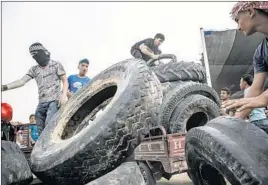  ??  ?? YOUTHS NEAR Khan Yunis in the Gaza Strip last week organize tires to be used in demonstrat­ions. The tires are often set on fire to create a smokescree­n.