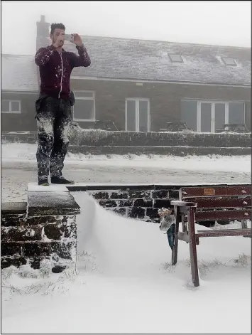  ??  ?? Frozen North: Dusted with snow, a man takes a photograph at Hartside Pass, Cumbria