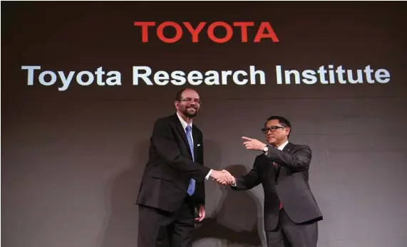  ?? Eugene Hoshiko / Associated Press ?? Toyota Motor Corp.’s Executive Technical Advisor Gill Pratt, left, and Toyota President Akio Toyoda, right, shake hands.