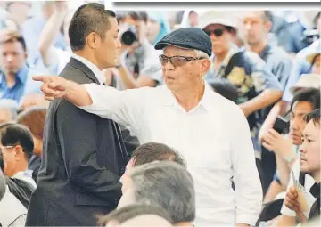  ??  ?? A man (centre) speaks out in protest against Abe during a memorial service to mark the 70th anniversar­y of the end of the Battle of Okinawa, at the Peace Memorial Park in Itoman, on Japan’s southern island of Okinawa, in this photo taken by Kyodo. —...