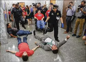  ?? SUSAN WALSH / AP ?? U.S. Capitol Police begin to detain protesters laying on the ground in an attempt to maintain order in the hallways outside the Senate Finance Committee hearing. The hearing on Capitol Hill in Washington on Monday is a last-ditch GOP push to overhaul...