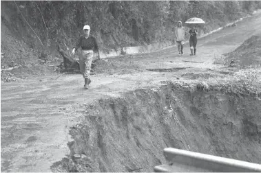  ?? Associated Press ?? Neighbors walk past a washed-out road in Alajuelita on Thursday on the outskirts of San Jose, Costa Rica. Tropical Storm Nate formed off the coast of Nicaragua on Thursday and was being blamed for at least 17 deaths in Central America as it spun north...