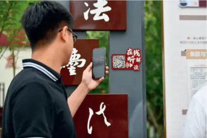  ?? ?? A visitor scans a QR code to learn more about the Civil Code at a park in Tianjin on August 20, 2020