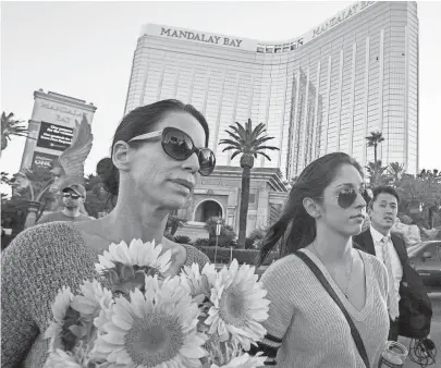  ?? SEAN LOGAN, THE (PHOENIX) ARIZONA REPUBLIC, VIA USA TODAY NETWORK ?? Christine Torres, left, and her daughter, Sydney Torres, carry flowers and a candle to a memorial for victims of the Las Vegas mass shooting on Tuesday.