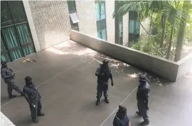  ?? Brian Kramer / Associated Press ?? Police and soldiers guard Parliament in Port Moresby, Papua New Guinea, after disgruntle­d police, military and prison guards assailed the building.