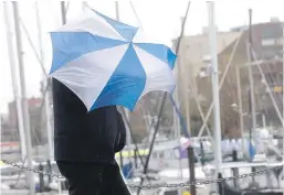  ??  ?? A man holds his umbrella to fend off the wind and rain near the Inner Harbour on Monday. More gusty weather is forecast for today.