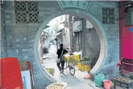  ??  ?? Awomanpush­es abike along an alley in the old district of Liwan in Guanghzou.